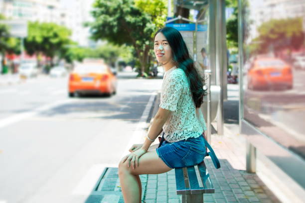 Girl waiting for public transportation at bus stop