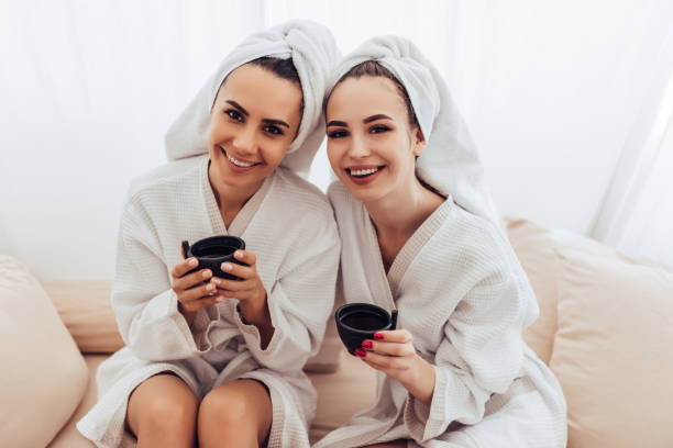 mujeres jóvenes en el salón de spa - bathrobe women cup towel fotografías e imágenes de stock