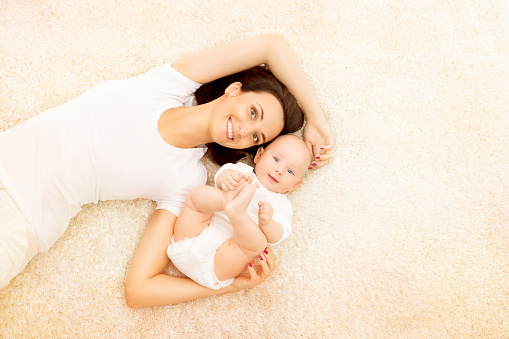 Mother and Baby, Happy Family Portrait, Mom with six months Kid Boy, Woman and Child in White Clothing Lying over beige Carpet