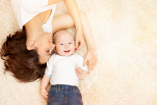 Mother and Baby, Happy Family Portrait, Mom with Kid Boy, Woman and Infant Child lying on Carpet background, top view