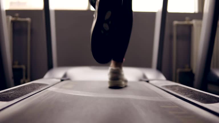 Slow motion footage of supposedly female legs in sneakers running on treadmill.