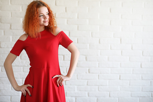 Red-haired girl student on a brick wall background