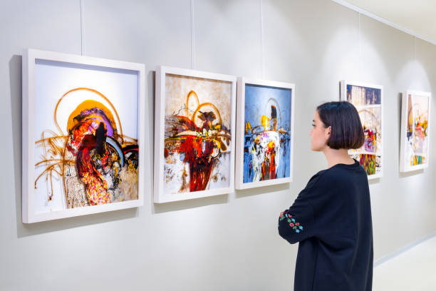 Artist's collection at showroom In a art gallery young woman visits an art exhibition and watches artist's collection. fine art painting photos stock pictures, royalty-free photos & images