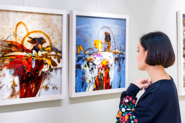 In a art gallery young woman visits an art exhibition and watches artist's collection. Focus on model.