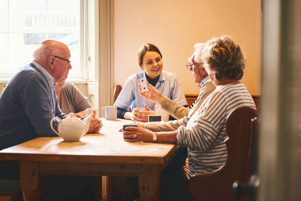 istock Nurse playing cards with elderly people at care home 941321144