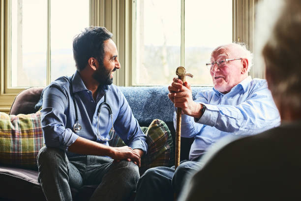 smiling doctor visiting senior man at home - senior adult old nursing home people imagens e fotografias de stock