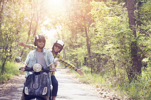 Couple riding their scooter through forest. life style idea concept