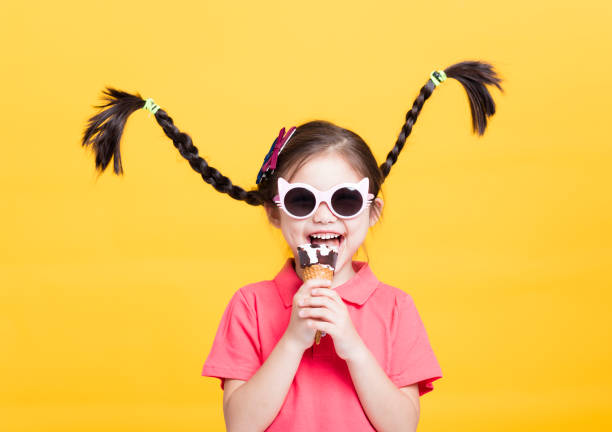 smiling little girl eating ice cream smiling little girl eating ice cream cone shape photos stock pictures, royalty-free photos & images