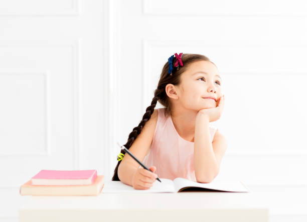 happy little girl  studying and thinking - child thinking writing little girls imagens e fotografias de stock