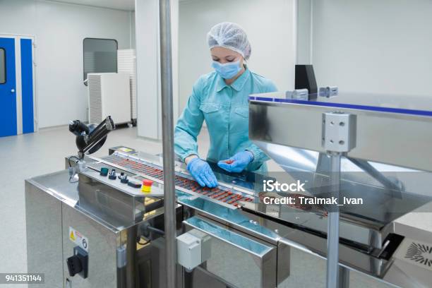 Pharmacy Industry Woman Worker In Protective Clothing Operating Production Of Tablets In Sterile Working Conditions Stock Photo - Download Image Now