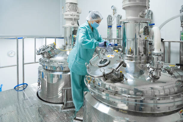 Pharmaceutical factory woman worker in protective clothing operating production line in sterile environment Pharmaceutical technician in sterile environment at pharmacy industry biology stock pictures, royalty-free photos & images