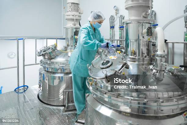 Pharmaceutical Factory Woman Worker In Protective Clothing Operating Production Line In Sterile Environment Stock Photo - Download Image Now