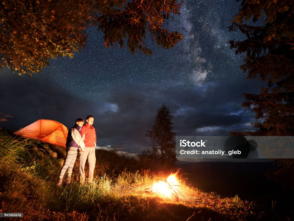 Noche Romántica De Pareja De Jóvenes En Las Montañas De Fuego Bajo El Cielo  Estrellado Foto de stock y más banco de imágenes de Actividades recreativas  - iStock