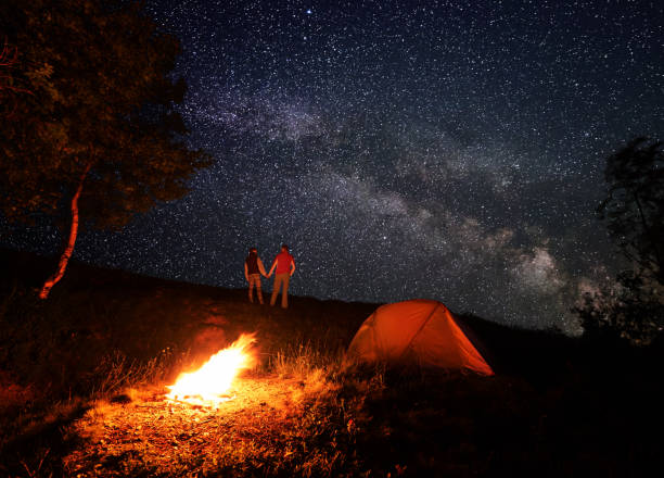 istock Night camping with a campfire under a bright starry sky with bright milky way 941352732
