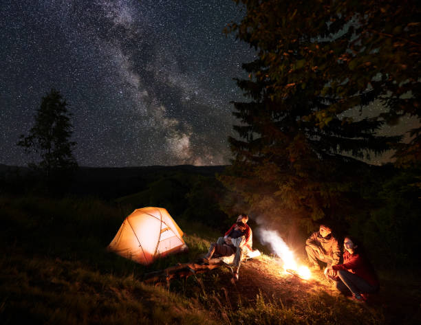 istock Two couples near campfire at night in the woods enjoying starry sky 941352806