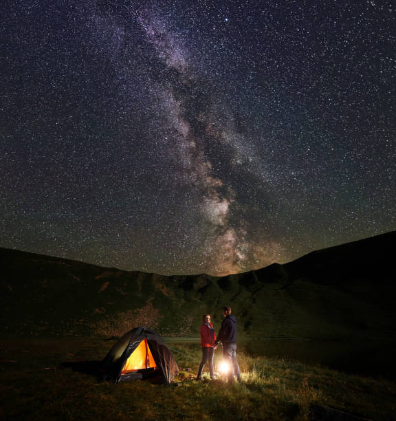 istock Lovers holding hands looking at each other between them burning fire under the night starry sky 941352834