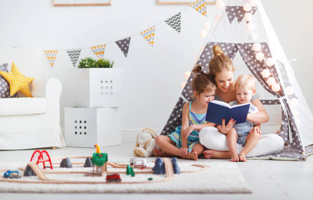 familie mutter zu kinderbuch im zelt zu hause lesen - child playroom parent indoors stock-fotos und bilder