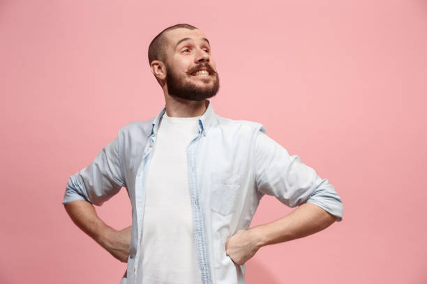 The happy business man standing and smiling against pastel background Happy business man standing and smiling isolated on pink studio background. Beautiful male half-length portrait. Young emotional man. The human emotions, facial expression concept. Front view. arrogance stock pictures, royalty-free photos & images