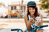 Young stylish woman with a bicycle using cell phone.