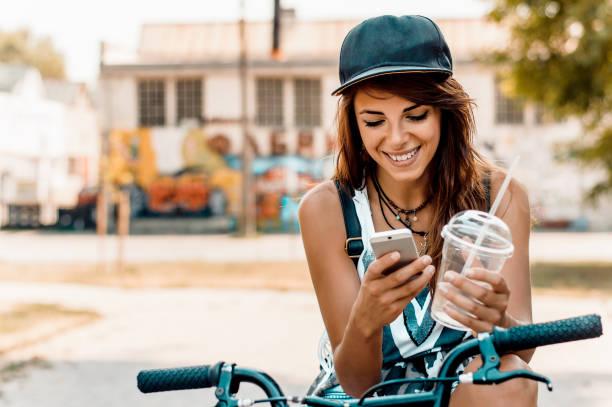 young stylish woman with a bicycle using cell phone. - cycling bicycle women city life imagens e fotografias de stock