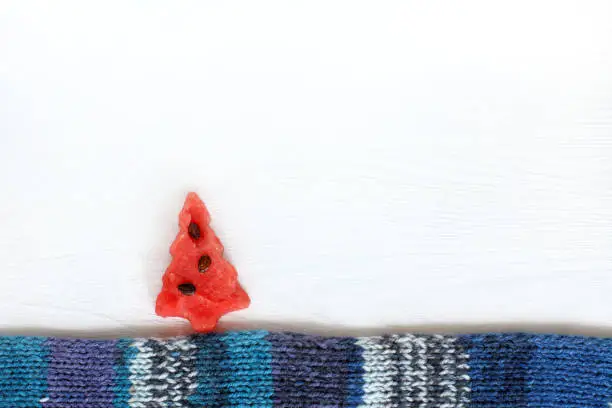 Flat layout of a sweet watermelon red Christmas tree on a blue scarf
