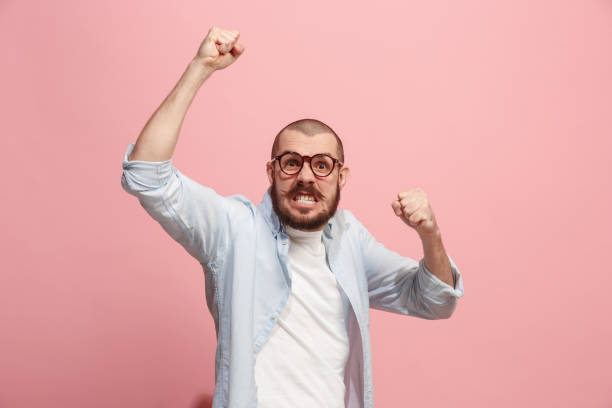 istock The young emotional angry man screaming on pink studio background 941373098