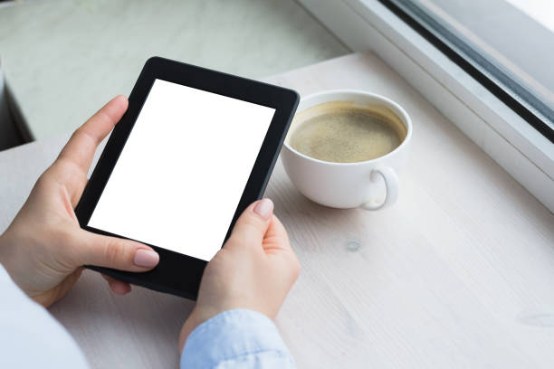 istock Young woman sitting by the window with an e-book 941373142