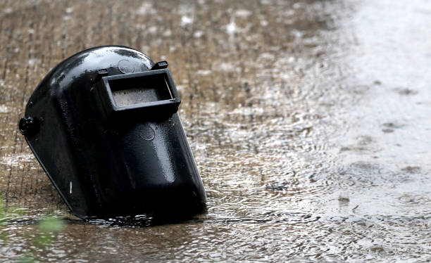 istock old black plastic welding mask with rain on water surface 941373322