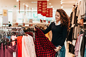 Brunette female customer selecting basic garments at the store.