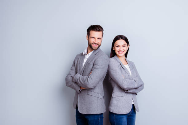 concept of partnership in business. young man and woman standing back-to-back with crossed hands against gray background - women business men beautiful imagens e fotografias de stock