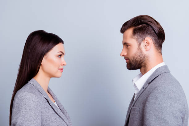 Concept of confrontation in business. Close up photo of two young serious confident people standing face-to-face to each other Concept of confrontation in business. Close up photo of two young serious confident people standing face-to-face to each other face to face stock pictures, royalty-free photos & images
