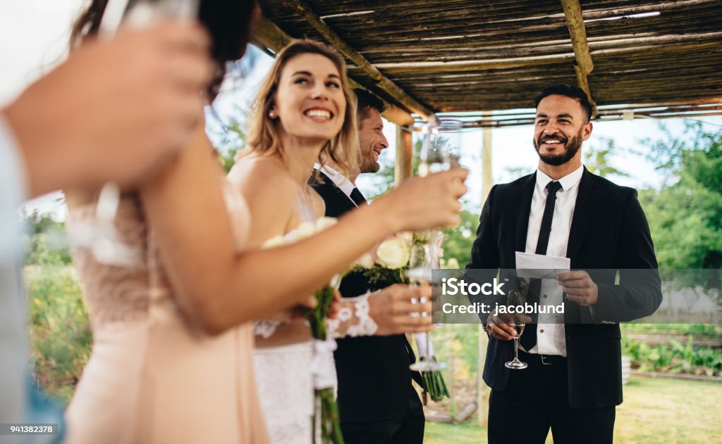 Best man performing speech for toast at wedding reception Best man performing speech for toast at wedding reception. Bride and groom listening to a speech at their wedding reception. Wedding Guest Stock Photo