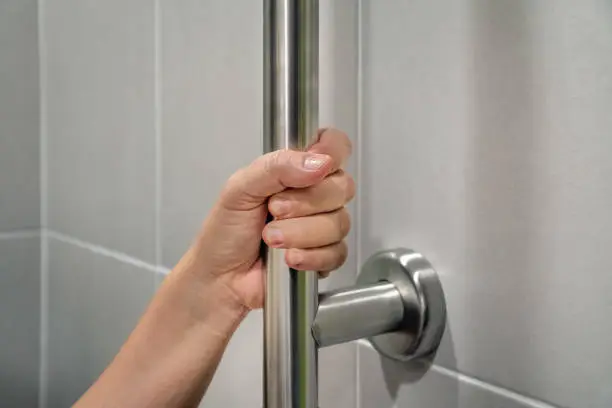 Photo of Woman holding on handrail in toilet.