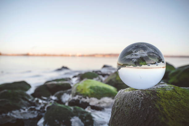 istock Glass orb on rocks by the sea 941387972