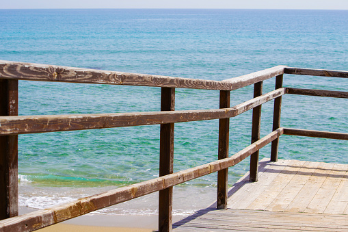 Wooden walkway with railing going down to the clear green sea. Cyprus, Turkey.