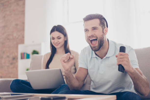 istock Married young people are spending their weekend at home together. He is watching game and she is searching for information in her laptop 941391512