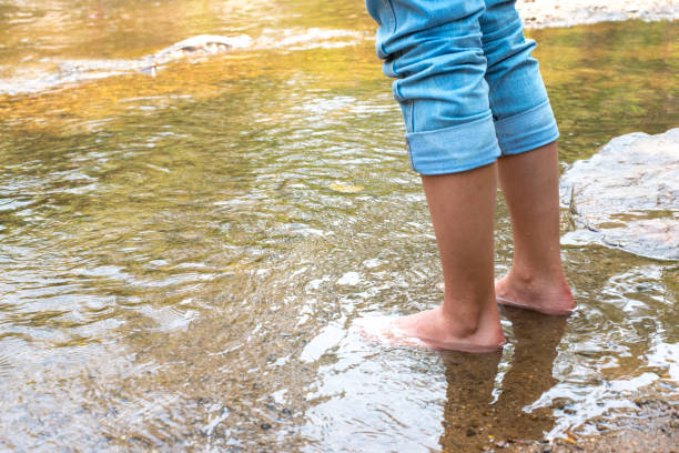 istock Close up leg Women's Jeans Stand on the stream river 941395920