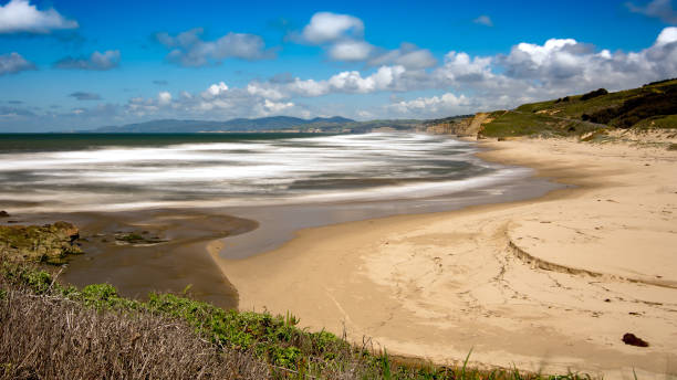 Sunset along the beach cliffs near half moon bay California. Clouds in the sky wit orange cliffs surrounding. The waves of the ocean crashing in