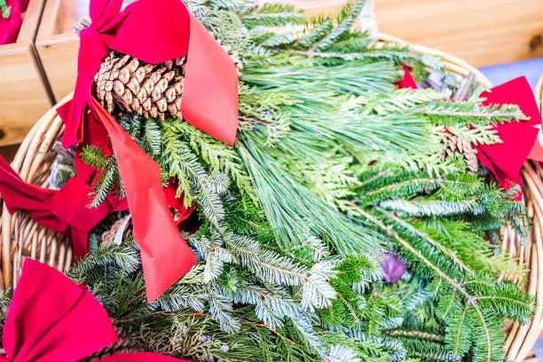 Closeup of green pine needle red ribbon mistletoe in basket on display in holiday season festive christmas store shop, juniper berries, pine cone pinecone