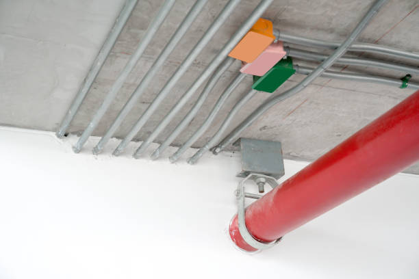 metal tube pole or pipe clamp hanging on concrete ceiling holding the red metal pipe - hose clip imagens e fotografias de stock
