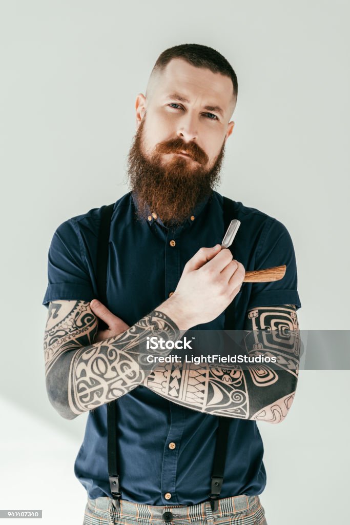 bel homme tatoué tenant razor et en regardant la caméra - Photo de Barbier - Salon de coiffure libre de droits