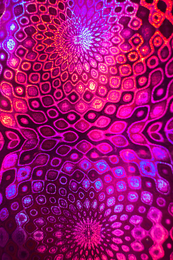 Decorative pink-violet pattern like mandalas on holographic paper. Selective focus.