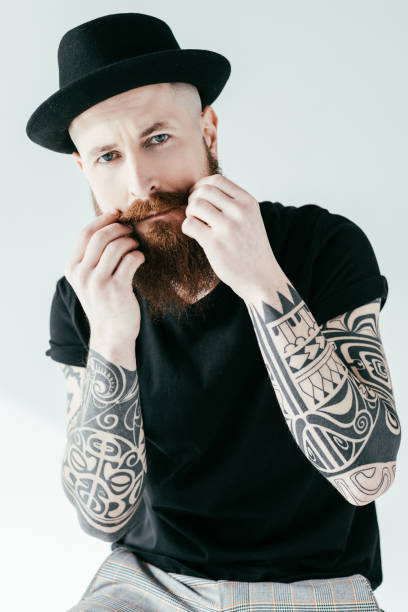 Bearded Tattooed Man Twisting Mustache And Looking At Camera Isolated On  White Stock Photo - Download Image Now - iStock