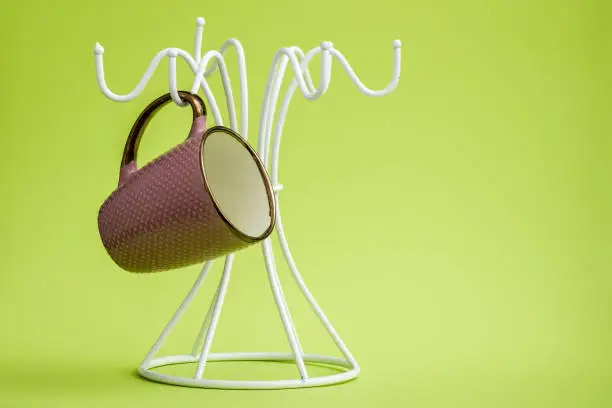 Coffee cups on a white hanger on green background