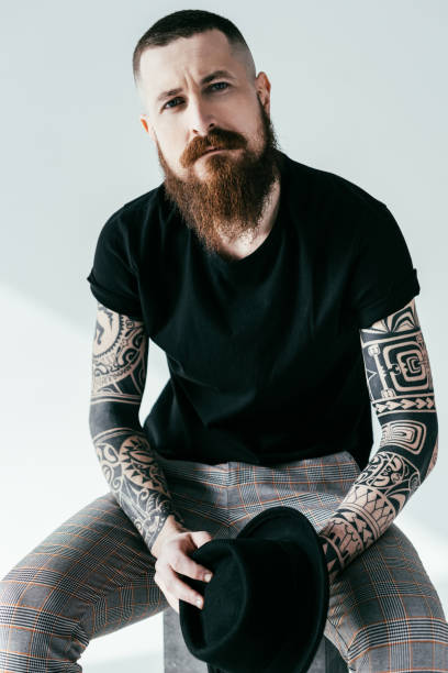 istock handsome bearded tattooed man looking at camera on white 941411568