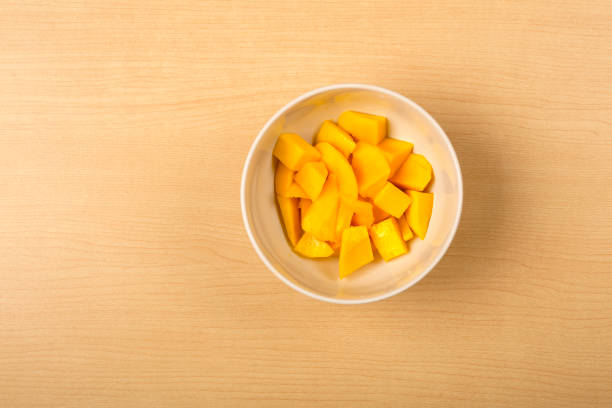 mango fresco picado en un tazón de fuente blanco sobre fondo de madera - healthy eating food and drink raw leek fotografías e imágenes de stock