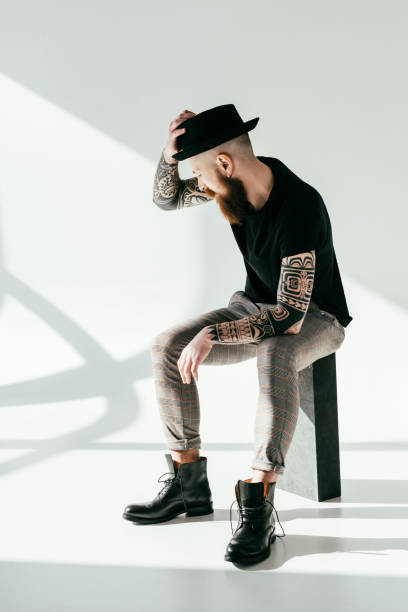 istock handsome bearded tattooed man touching hat on white 941413222