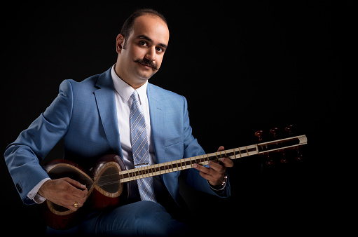 Persian musician posing on black background.
