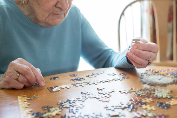 close up de mujer senior relajante con rompecabezas en casa - estimulacion cognitiva fotografías e imágenes de stock