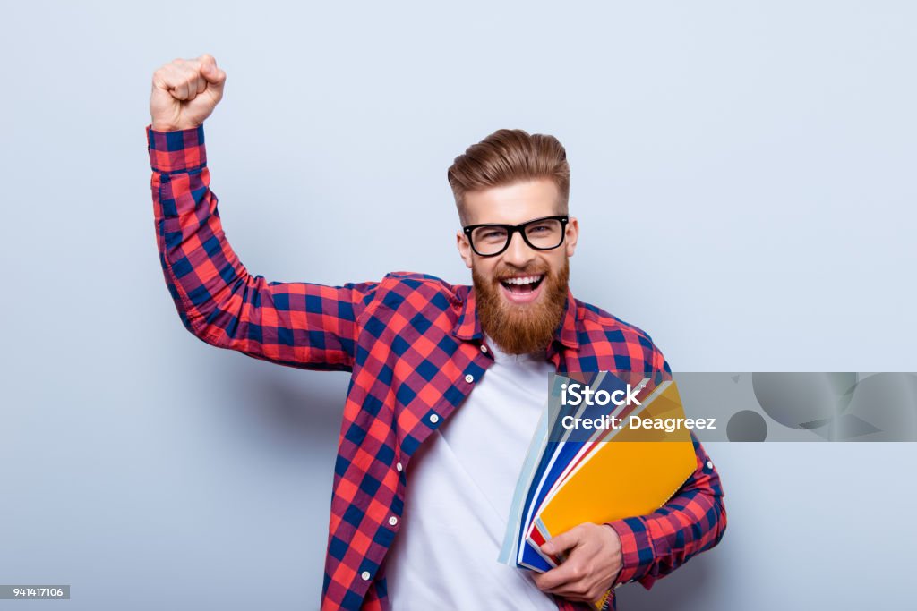 Junge fröhliche Studentin in Gläsern und im karierten Hemd mit Büchern in Händen feiert Ende der Prüfungen - Lizenzfrei Lernender Stock-Foto